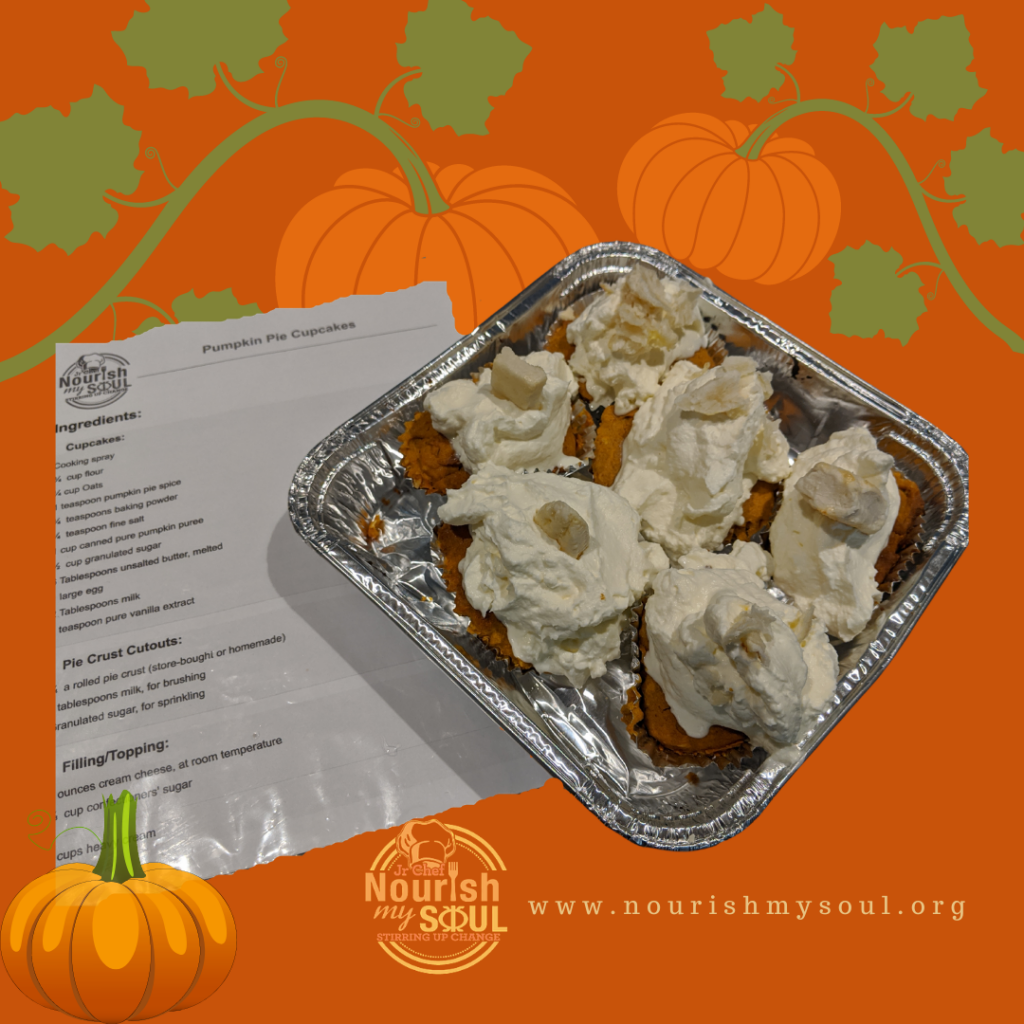 Tin filled with cupcakes topped with whipped cream frosting, a recipe beside it, and pumpkins in the background
